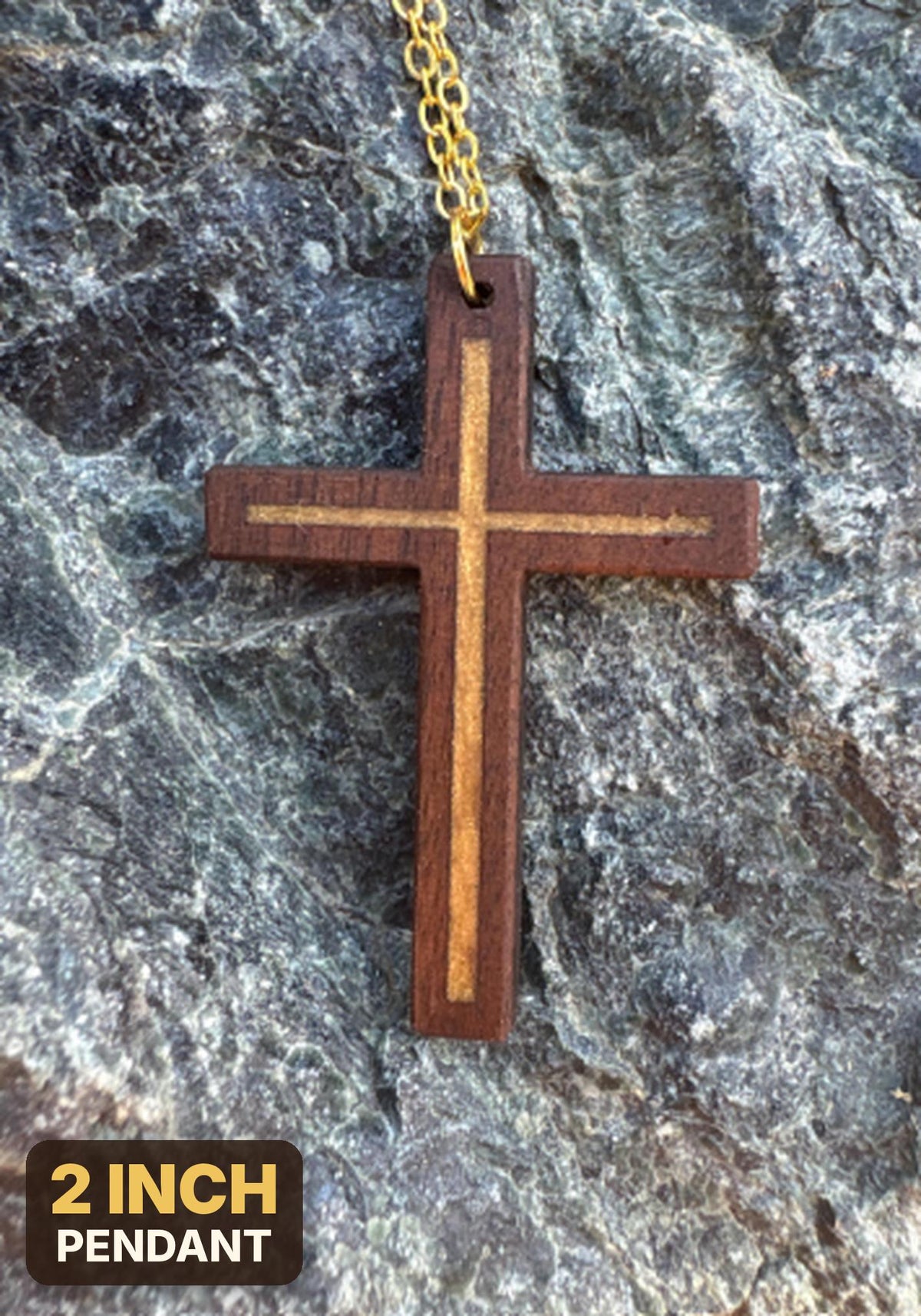 Gold resin-inlay walnut cross necklace with gold-colored chain on dark rock, labeled 2-inch pendant