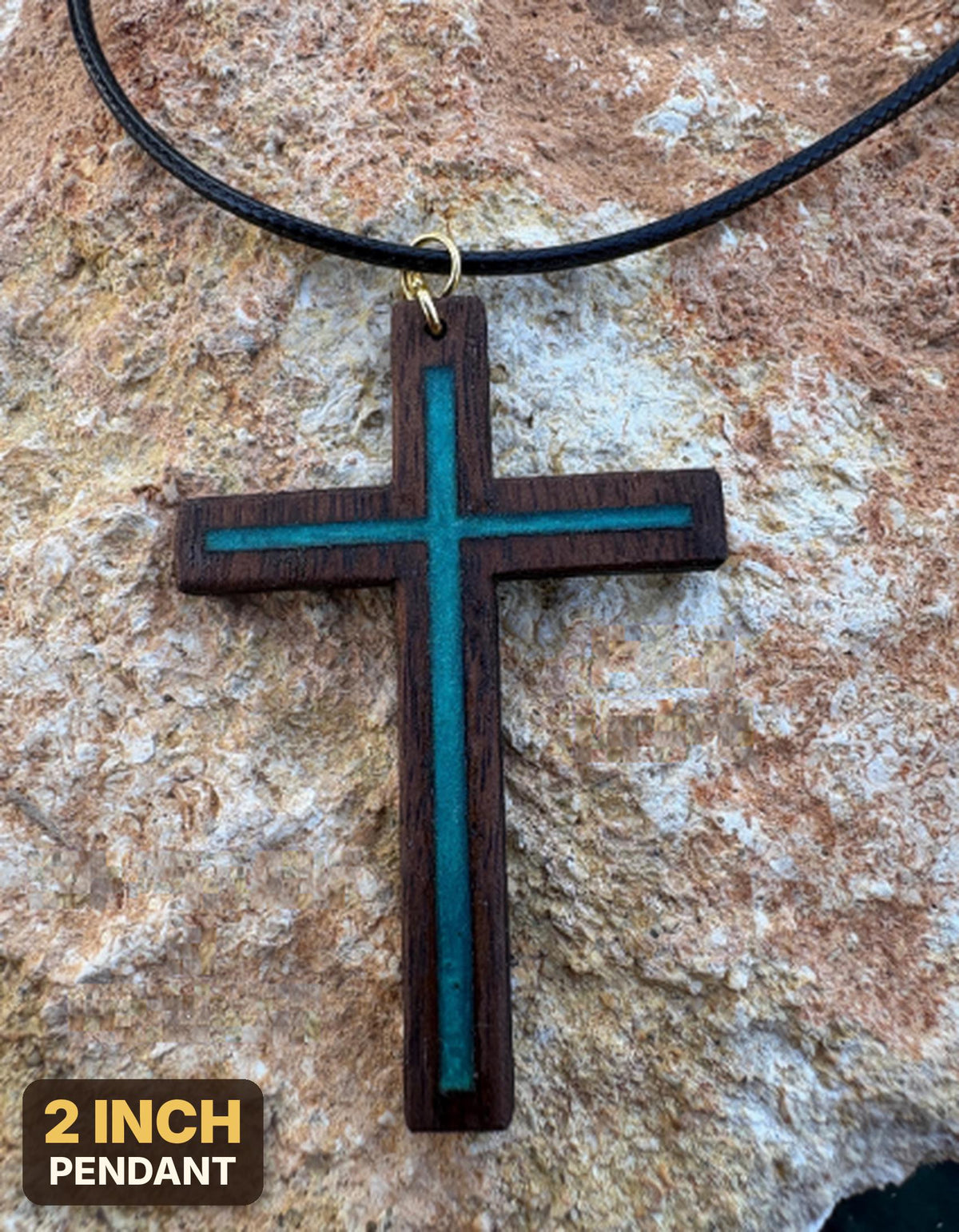 Turquoise resin-inlay walnut cross necklace on black cord over tan rock, labeled 2-inch pendant